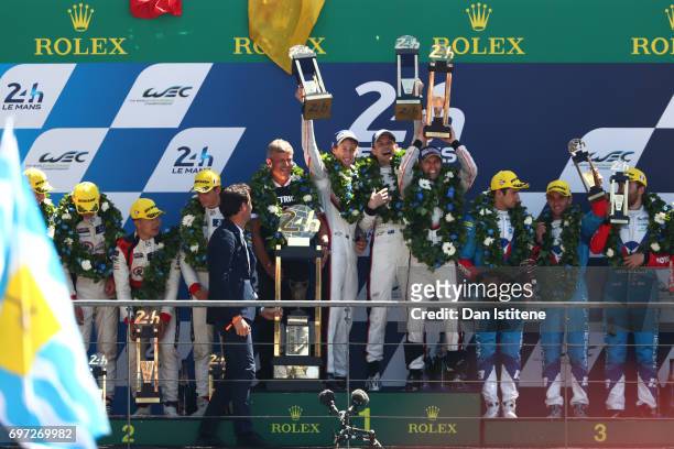 Brendon Hartley, Earl Bamber and Timo Bernhard of the Porsche LMP Team lift their trophies as they celebrate on the podium with Vice President of...