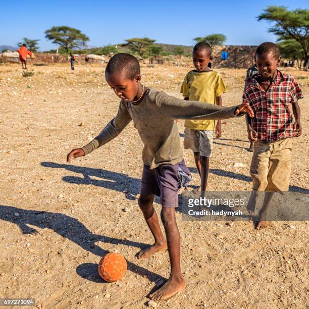 barfuß afrikanische kinder spielen fußball im dorf, osten und afrika - poor kids playing soccer stock-fotos und bilder