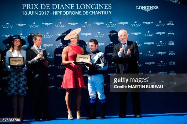 French jockey Stephane Pasquier smiles as he receives the trophy by US skier Mikaela Shiffrin after winning the Prix de Diane, a 2,100-meters flat...