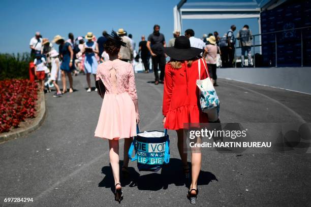 Two women carry a shopping bag as they arrive prior to the start of the Prix de Diane, a 2,100-meters flat horse race, on June 18, 2017 at the...