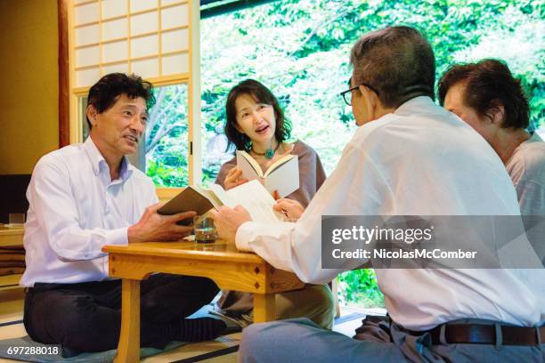 vier volwassen en ouderen-japanse vrienden genieten van boekenclub in restaurant - reading books club stockfoto's en -beelden