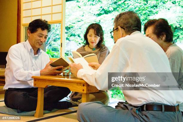 vier volwassen en oudere japanse vrienden deelnemen aan boekenclub in restaurant - reading books club stockfoto's en -beelden