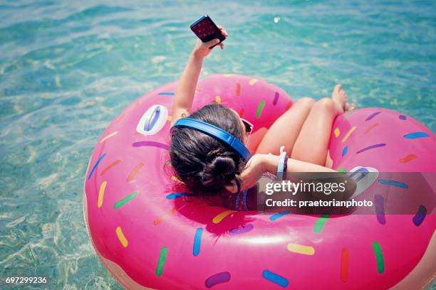 little girl is floating in the water and listening the music - beach music stock pictures, royalty-free photos & images