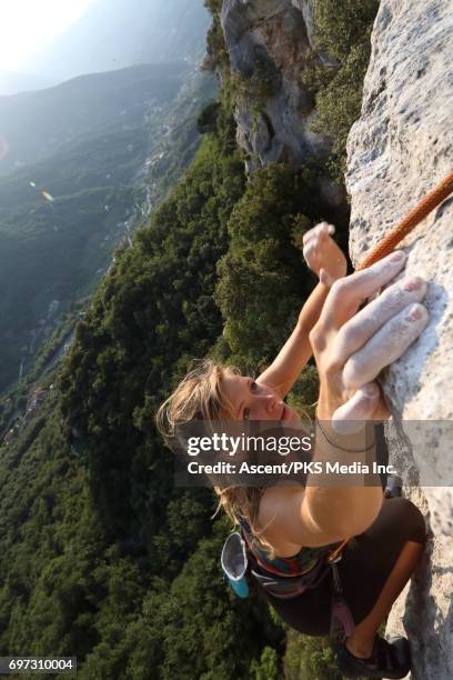 young female climber ascends vertical rock, above valley - grittywomantrend stock pictures, royalty-free photos & images