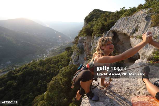 young female climber ascends vertical rock, to belayer - escalada en roca fotografías e imágenes de stock