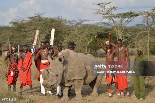 Maasai warriors pose with Sudan, the only male of the last three northern white rhino sub-species on the planet, on June 18, 2017 following a charity...