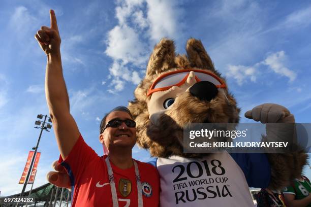 Chile supporter poses with a person dressed as Zabivaka, the mascot of the 2018 FIFA World Cup, ahead of the 2017 Confederations Cup group B football...