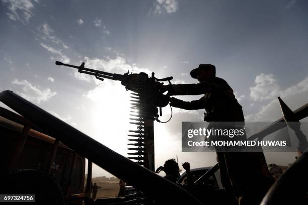 Shiite Huthi rebel stands on a vehicle mounted with a machine-gun during a gathering to mobilise more fighters to battlefronts to fight Yemeni...