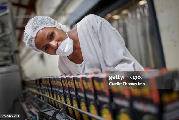 Thika, Kenya An employee checks a conveyor belt on which Tetra Paks with fruit juice are transported. Production of juice at beverage manufacturer...