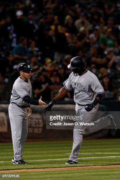 Chris Carter of the New York Yankees is congratulated by third base coach Joe Espada after hitting a home run against the Oakland Athletics during...