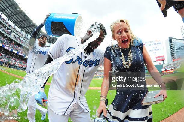 Brandon Phillips of the Atlanta Braves is doused by Matt Kemp with a water cooler, along with Braves reporter Kelsey Wingert, after kocking in the...