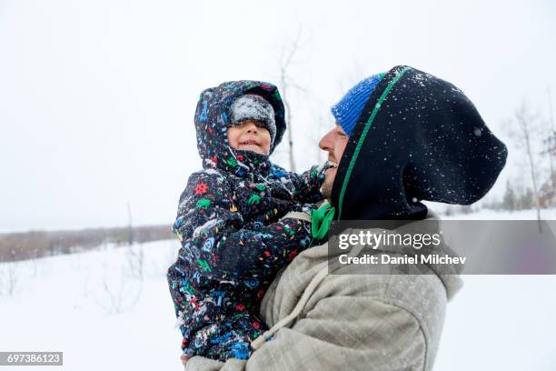 Kid covered with snow laughing with his father.