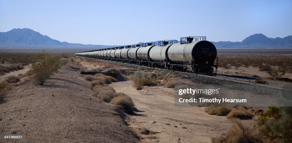 Tanker cars on railroad tracks; mountains beyond