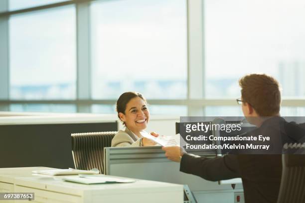 smiling businesswoman holding paperwork in office - leanintogether stock pictures, royalty-free photos & images