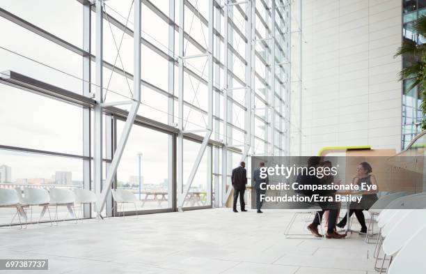 business people discussing plans in modern lobby - hotelfoyers stock-fotos und bilder