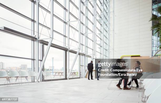 business people discussing plans in modern lobby - lobby photos et images de collection