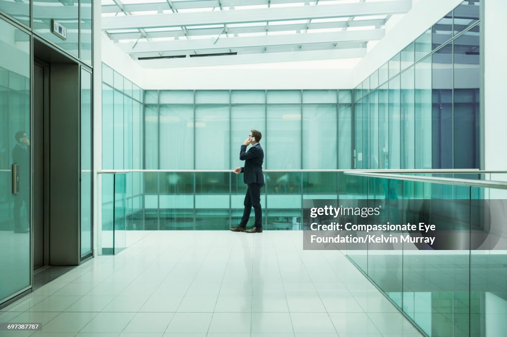 Businessman using cell phone on atrium balcony