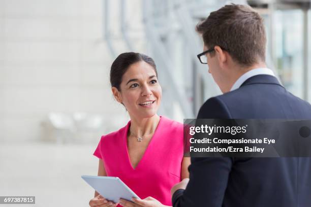 business people using digital tablet in lobby - pink suit stockfoto's en -beelden