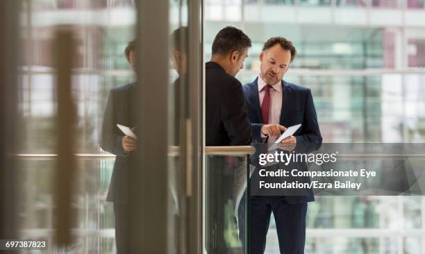 businessmen discussing project on office balcony - atrio-característica-arquitectónica fotografías e imágenes de stock