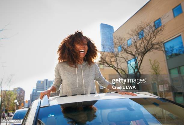 young woman standing out of sunroof - car roof stock pictures, royalty-free photos & images
