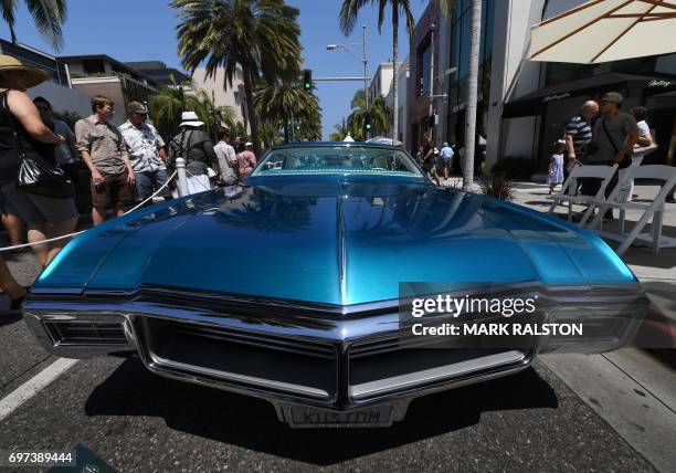 Car enthusiasts look at a 1968 Buick Riviera custom car on display at the Rodeo Drive Concours Delegance car show in Beverly Hills, California on...