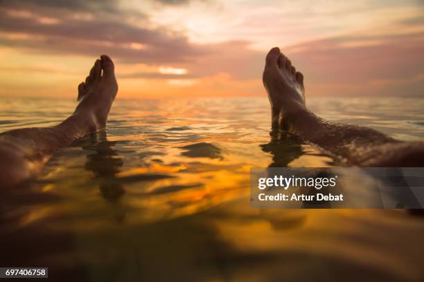 traveler guy from personal perspective floating on water watching the sunset light over the horizon in the gili islands. - floating on water stock pictures, royalty-free photos & images