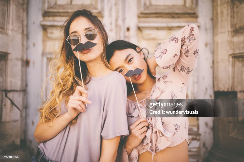 Women playing with mustaches on sticks in city streets