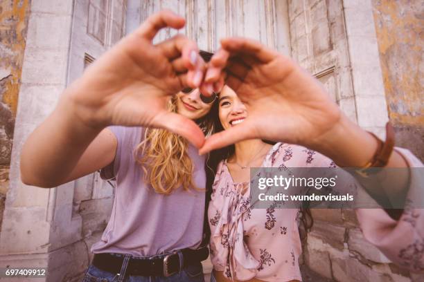 vrouwen in de stad maken van hart vorm met hun handen - two finger stockfoto's en -beelden