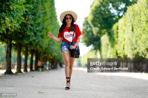 Sarah Benziane, fashion blogger, wears a Naive New Beater red t-shirt with the printed inscription "A La Folie" and a printed heart, a Pimkie blue...