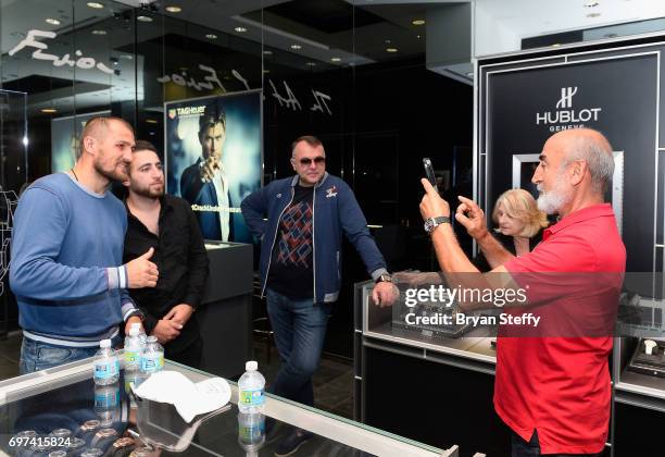 Boxing trainer Egis Klimas looks on as boxer and Hublot ambassador Sergey Kovalev poses with fans during their visit to the Hublot Boutique at The...