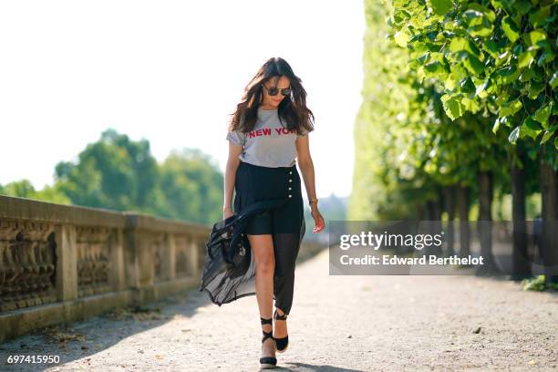 Sarah Benziane, fashion blogger Les Colonnes de Sarah, wears a The Kooples ruffled black skirt, a New Look t-shirt with the printed inscription "New...