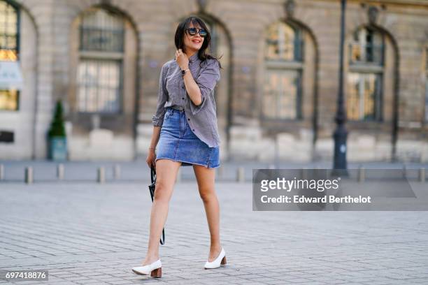 Sarah Benziane, fashion blogger, wears a The Kooples gingham shirt, a New Look blue denim skirt, an Ali Express bag, sunglasses, and Zara white...