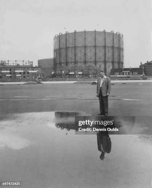 Head groundsman Bert Lock and the landmark gasometer are reflected in a pool of water on the wicket of the cricket pitch as bad weather and rain...