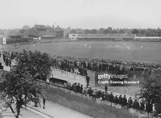 Schoolboy looks up from the street outside the ground as crowds of spectators in the grandstand and the Pavilion watch Bill Woodfull and Bill...