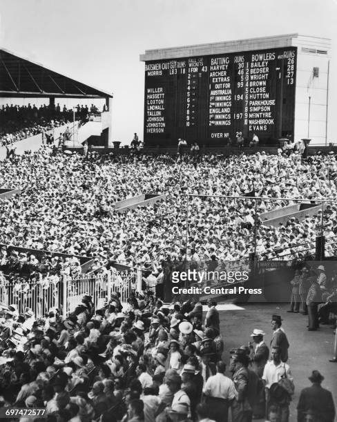 The scoreboard forms the backdrop to the crowds of spectators in the grandstand to watch the 2nd Test match of The Ashes series between Australia and...