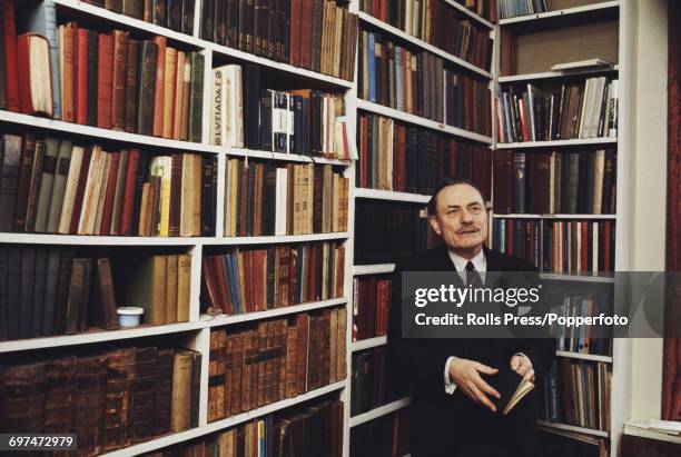 British Conservative Party politician and Member of Parliament for Wolverhampton South West, Enoch Powell pictured holding a book in his library...