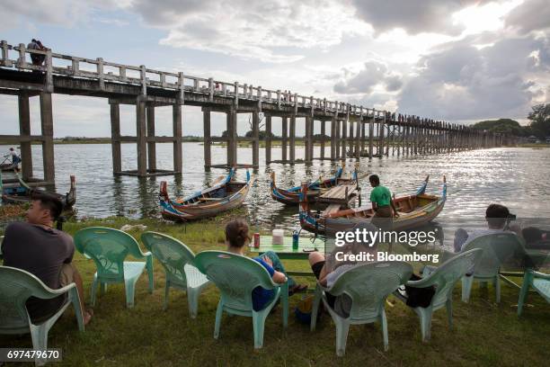 Visitors and tourists sit at the shore of Taungthaman Lake near U Bein Bridge in Mandalay, Myanmar, on Saturday, June 10, 2017. When the country...