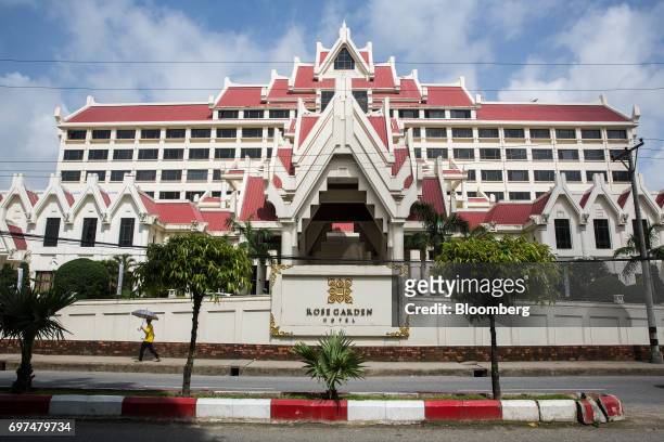 Man holding an umbrella walks past the Rose Garden Hotel in Yangon, Myanmar, on Monday, June 12, 2017. When the country opened to the outside world...