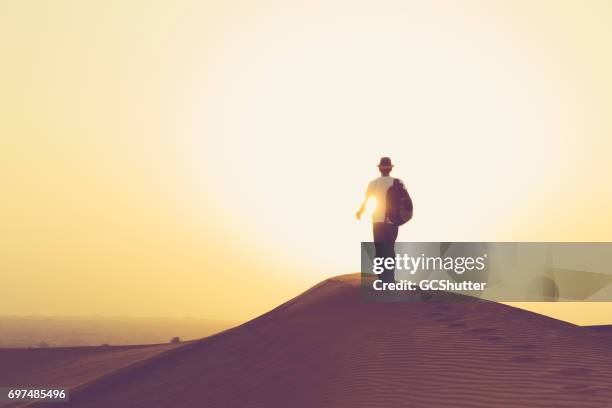 adolescent, marchant vers le soleil levant sur les dunes arabian - qatar desert photos et images de collection
