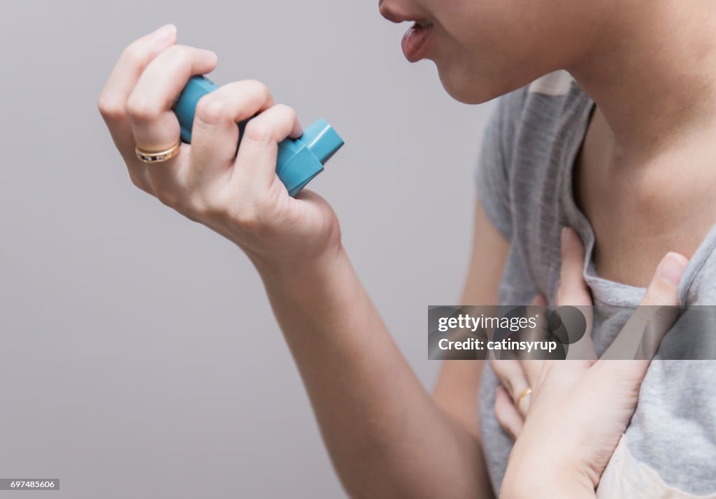 Mujer asiática con un inhalador de cartucho presurizado extiende faringe, broncodilatador