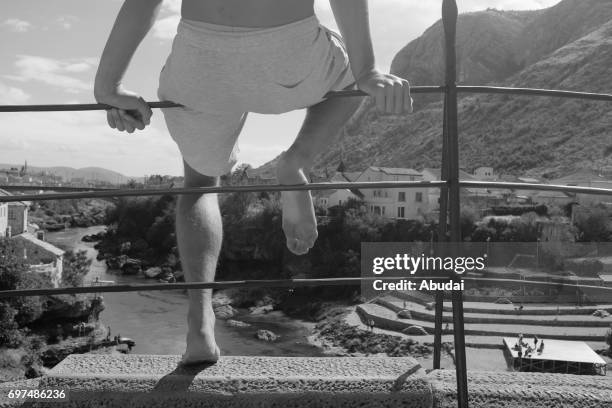 man getting ready to jump from mostar bridge. - mostar stock-fotos und bilder