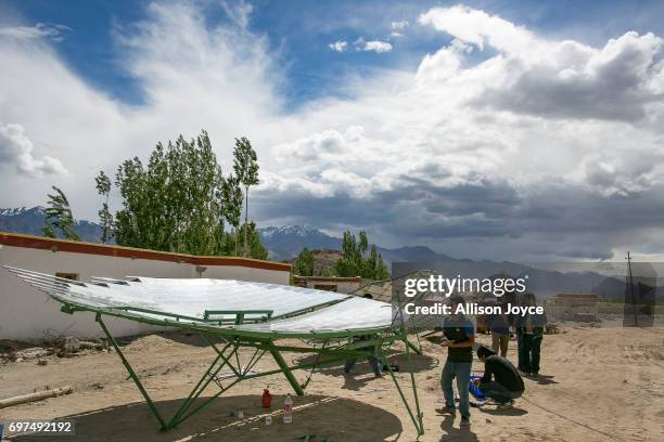 Workers with the Ladakh Renewable Energy Development Agency work to repair a solar thermal dish at a school in Choglamsar on June 12, 2017 in Ladakh,...