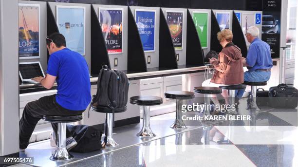 Travellers sit to use their computers at a WiFi station on a concourse at Chicago's O'Hare International Airport in Chicago, Illinois on May 25,...