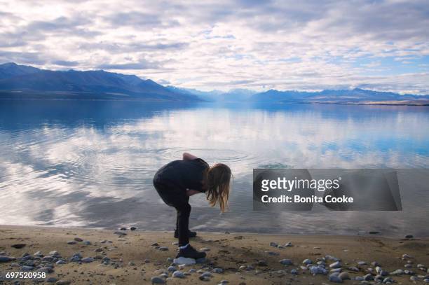 girl skimming stones at lake pukaki, mount cook - skimming stones stock pictures, royalty-free photos & images