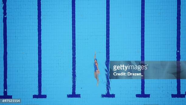 drone point of view on swimming pool and female backstroke swimmer - swimming stock pictures, royalty-free photos & images