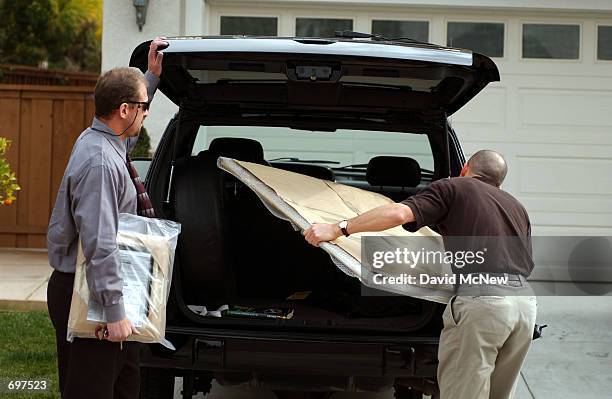 Men from a local photo studio deliver large prints from a recent familty portrait session to the home of the Damon and Brenda van Dam and their...