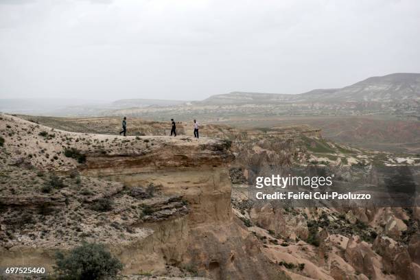 three people on the top of cliff at ürgüp nevşehir province, central anatolia region of turkey. - nevşehir province 個照片及圖片檔