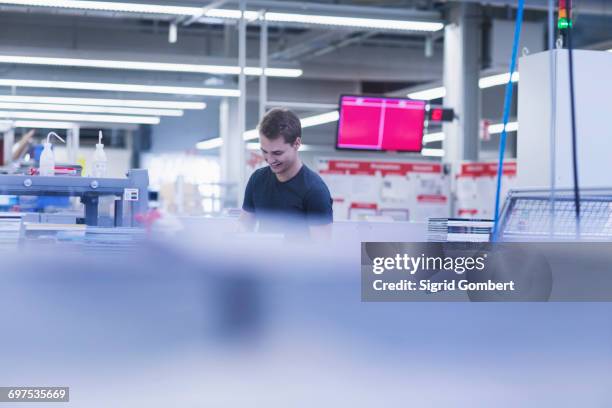 young man working in books printing industry, bremgarten, hartheim am rhein, baden-wuerttemberg, germany - tube néon photos et images de collection