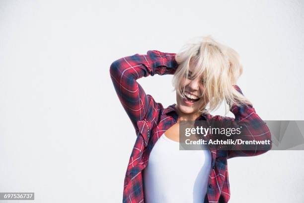 young woman playing with her hairs and dancing in front of wall, bavaria, germany - dancing funny carefree woman stock pictures, royalty-free photos & images