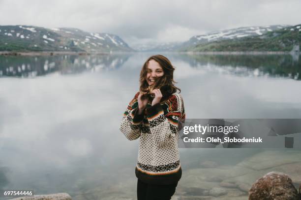 frau in strickpullover lachen in der nähe der fjord in norwegen - knitted stock-fotos und bilder